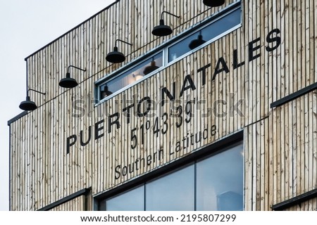 Building with a sign saying Puerto Natales 51degrees 43 minutes 39 seconds Southern Latitude. Puerto Natales, Chile Royalty-Free Stock Photo #2195807299