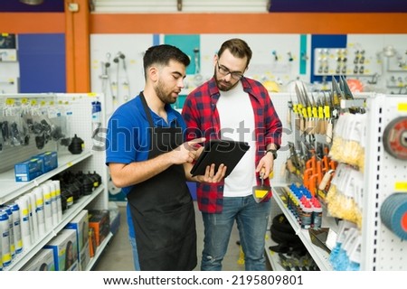 Young man working in customer assistance at the hardware store and talking with a client shopping at the hardware store Royalty-Free Stock Photo #2195809801