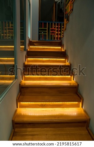 Illuminated staircase with wooden steps and illuminated at night in the interior of a large house. Royalty-Free Stock Photo #2195815617