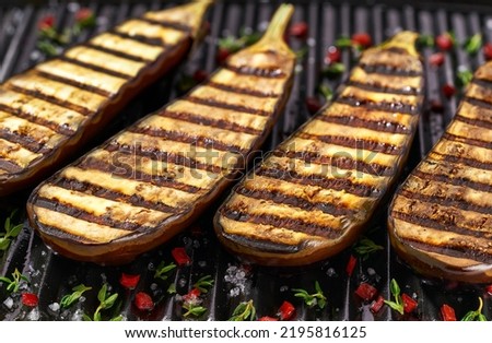 halves grilled eggplants , with chilli pepper and spices. Ideas for barbecues and grill parties.Healthy summer veggie food. Fried eggplant slices in a grill. Royalty-Free Stock Photo #2195816125
