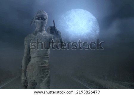 Mummy standing and showing thumb up with a night scene background. Halloween concept