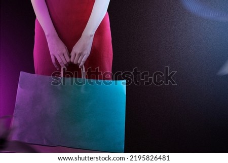Woman carrying a shopping bag with a black background. Cyber Monday concept