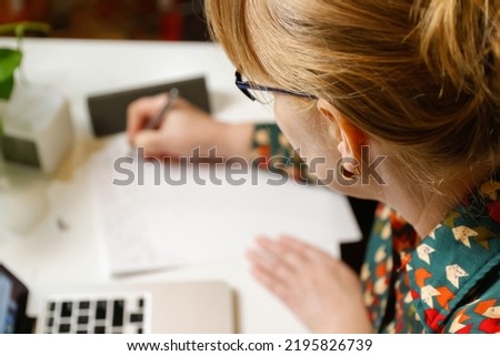 Defocus female hand writing pen. Unrecognizable elegant woman working on computer at office. Start or finish of a work day. Workspace. Paperwork. Time for work. Closeup businesswoman. Out of focus.