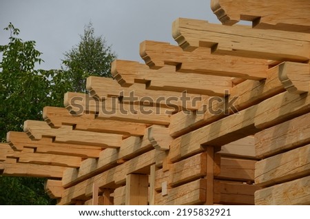 a carpenter built a log cabin with rough hewn beams. wood planing was not done before. authentic craftsmanship wooden log cabin. mortises for placing roof beams. gouging wood, ax, cut, truss,  Royalty-Free Stock Photo #2195832921
