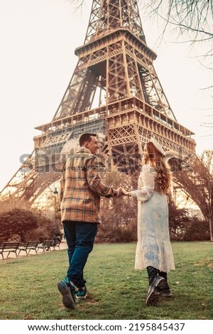 A couple in Paris with the Eiffel Tower in the background. Romantic trip, honeymoon in Europe. France city of love. Follow me. Love.