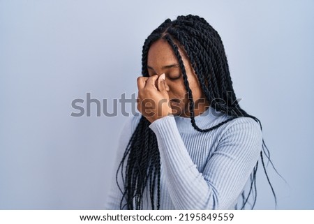 African american woman standing over blue background tired rubbing nose and eyes feeling fatigue and headache. stress and frustration concept. 