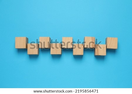 Wooden cubes on light blue background, flat lay