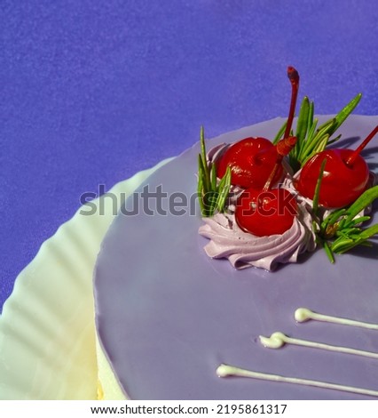 Mousse dessert decorated with cherries and rosemary sprigs on a white plate on a purple background. Delicious birthday cake.
