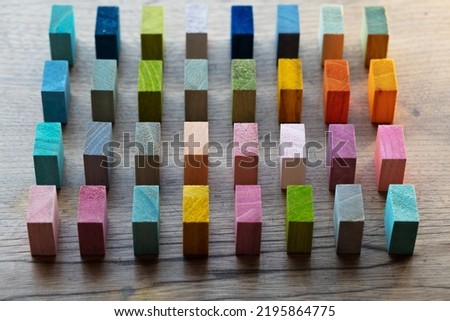 Spectrum of colorful wooden blocks aligned in intervals on a rustic old wood table. Japanese Colors set. Background or cover for something creative, diverse, or in variations. Shallow depth of field.