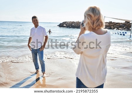 Middle age man and woman couple making photo using camera at seaside