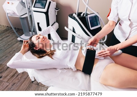 Woman getting treatment on abdomen to burn fat and build muscles, slimming technology Royalty-Free Stock Photo #2195877479