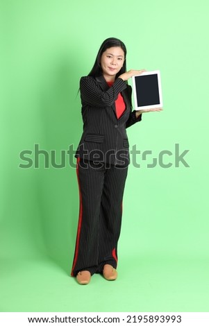 The Asian businesswoman standing on the pastel green background.