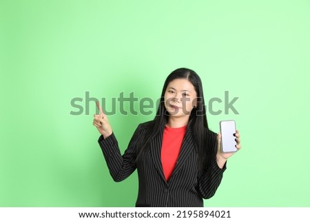 The Asian businesswoman standing on the pastel green background.