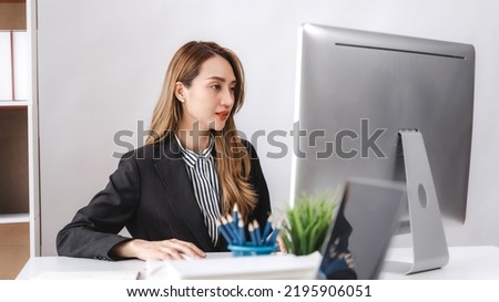 Portrait of asian pretty business woman smiling at at workplace, working with desktop pc in office workspace.
