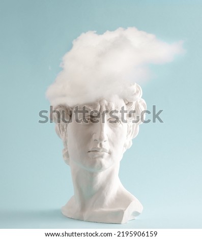 White plaster statue head of David with cloud  on pastel blue background. Minimal art poster. Royalty-Free Stock Photo #2195906159