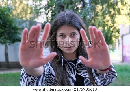 A young tall girl with long dark straight hair stretched out her hands palms forward
