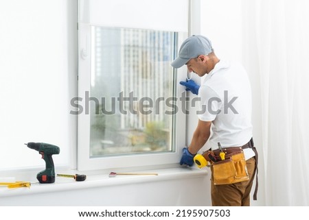 master puts a new double-glazed window in a plastic window Royalty-Free Stock Photo #2195907503