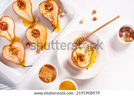 Honey or marple syrup roast pears with walnuts on light background. Vegetarian diet health delicious dessert. Top view. Royalty-Free Stock Photo #2195908979