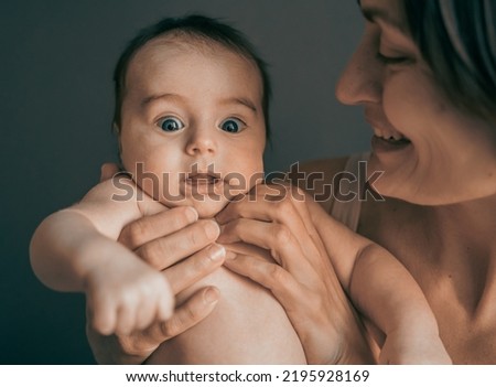 Mom, mummy, young mother with little baby daughter. Mum kissing and hugging child. Newborn cute happy girl smiling in woman hands. Happiness for parents in family. Aged parents, parenting, motherhood.
