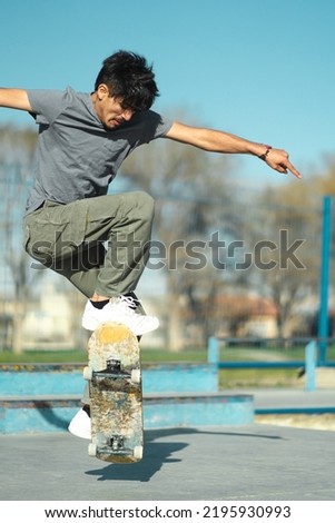 Latin American skater boy doing trick with skate board. Close up. Vertical photo