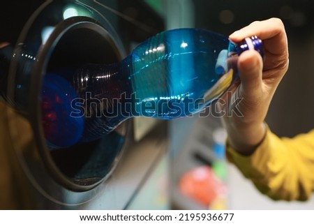 Woman puts bottle in automatic bottle recycling machine. Reverse vending recycling machine. Royalty-Free Stock Photo #2195936677