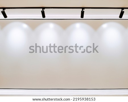 Photo of white empty wall copy space, Gallery Interior with illuminated black track light on cieling for stock. Royalty-Free Stock Photo #2195938153