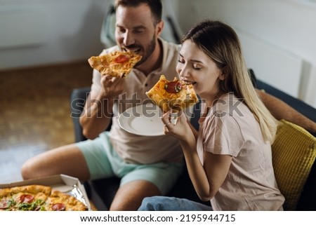 Happy young couple  eating pizza for lunch in the living room