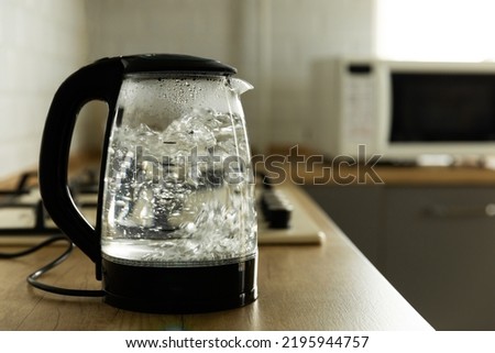 Modern electric transparent kettle on a wooden table in the kitchen.Kettle for boiling water and making tea.Home appliances for making hot drinks.Space for copy.Place for text. Royalty-Free Stock Photo #2195944757