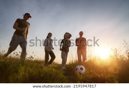 Happy family playing soccer. Young active people enjoying sunny summer evening outdoor. Healthy sport for kids. Football game club.