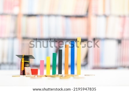 Education and life long learning is the key success, educational concept : Black graduational cap or a mortarboard, textbooks, increasing height color bar graphs with blurred bookshelf background.