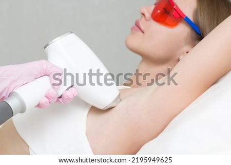 A young blonde woman undergoes the procedure of laser hair removal of her armpits in a beauty clinic Royalty-Free Stock Photo #2195949625