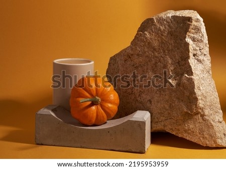 Pumpkin on the podium on the background of stone and ceramic pedestal. Yellow background with space to copy. Template for your design. High quality photo