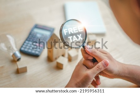 Businessman calculating annual tax deduction Financial analysis, tax payment, magnifying glass and Free Tax text. Royalty-Free Stock Photo #2195956311