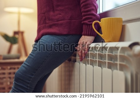 Woman heating on a chilly winter day, energy and gas crisis, cold room, heating problems. Royalty-Free Stock Photo #2195962101