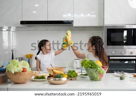 

Asian families are happy to cook in a modern kitchen.  Happy smiling young Asian  family with preschool kids have fun cooking  in modern kitchen home in the morning.