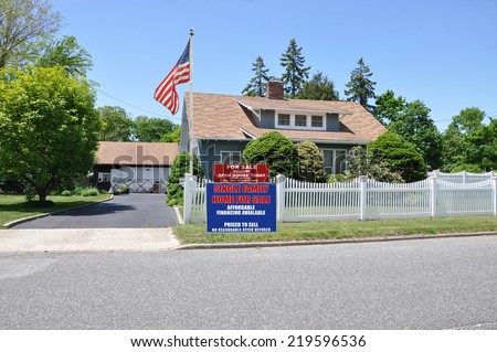 American Flag Pole Real Estate For Sale Open House Welcome sign front yard of suburban cape style home residential neighborhood clear blue sky USA