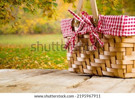 Against the background of wonderful autumn nature, a carpet of golden leaves, a beautifully decorated picnic basket on a simple wooden table. Family traditions, Thanksgiving celebration.