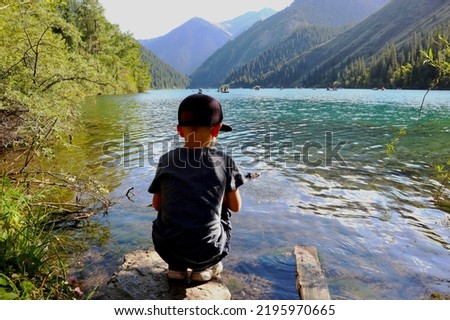 a little boy on the lake controls a toy boat