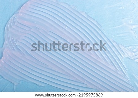 Abstract patterns of transparent moisturizing facial gel. The texture of the cosmetic product is smeared on a blue background.