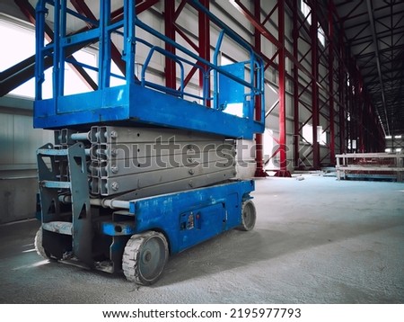Hydraulic lifting platform at construction site. Scissor lift platform inside of industrial building. Cherry picker or aerial manlift Royalty-Free Stock Photo #2195977793