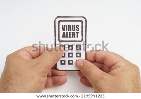 Technology and security concept. On a white background, in the hands of a person, a cardboard model of a telephone with an inscription on the screen - Virus alert