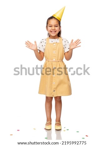 birthday, childhood and people concept - portrait of smiling little girl in dress and party hat over white background