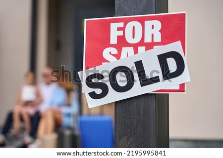 Close up sign for sale. Family sitting on steps