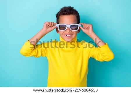 Photo of cheerful cute satisfied boy arm touch eye accessory enjoy holiday isolated on aquamarine color background