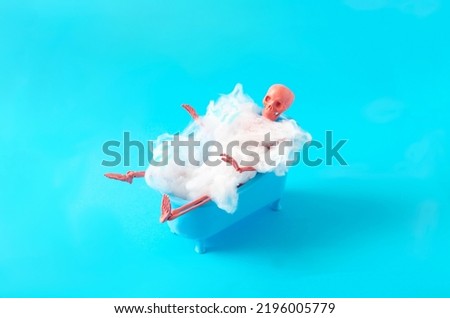 A skeleton taking a bath in a blue bath tube filled with spider web against blue background. Halloween party invitation concept. Funny and spooky artistic design for advertisement or banner