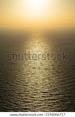 Beautiful sunset over the sea. Orange sunset in the bright sky over the calm sea with sunlight reflection. Travel postcard concept, beautiful wallpaper, meditating picture. Vertical.