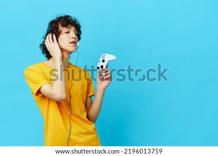 gamer plays with joystick in yellow t-shirts isolated backgrounds