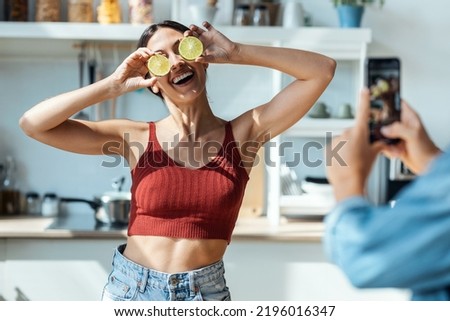 Shot of beautiful young couple having fun and playing with lemon slices on the eyes in the kitchen at home.