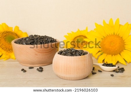 Sunflower seeds and flowers on wooden table.