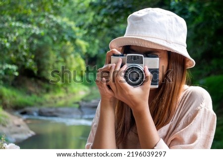 A woman gesturing with a toy camera to take pictures.
